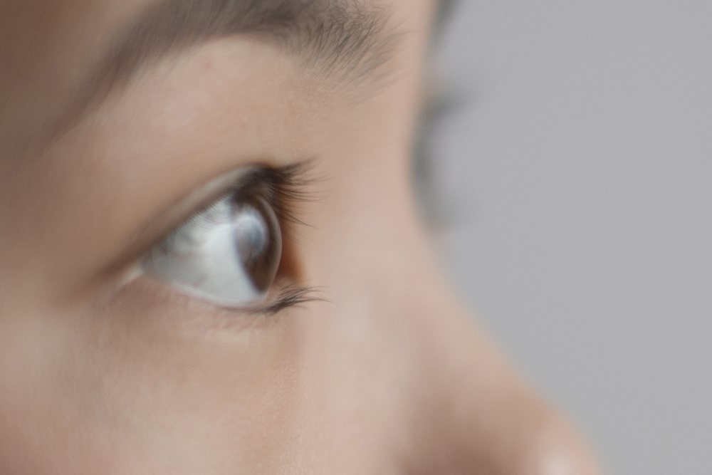 Close-up profile of a boy's face showing a visible brown eye, delicate eyelashes, and smooth skin texture, Art, portrait, emotional.
