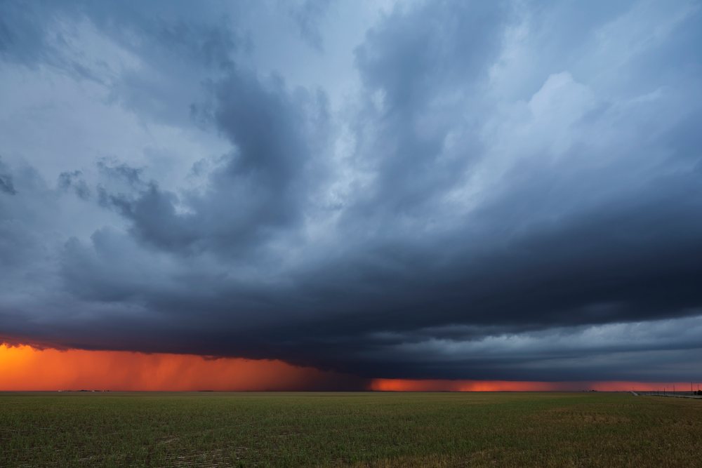 Supercell thunderstorm with dark storm clouds and rainfall over flat farmland at Sunset, Storm Chasing, Weather, Environmental Issues, Burlington, Colorado, USA.