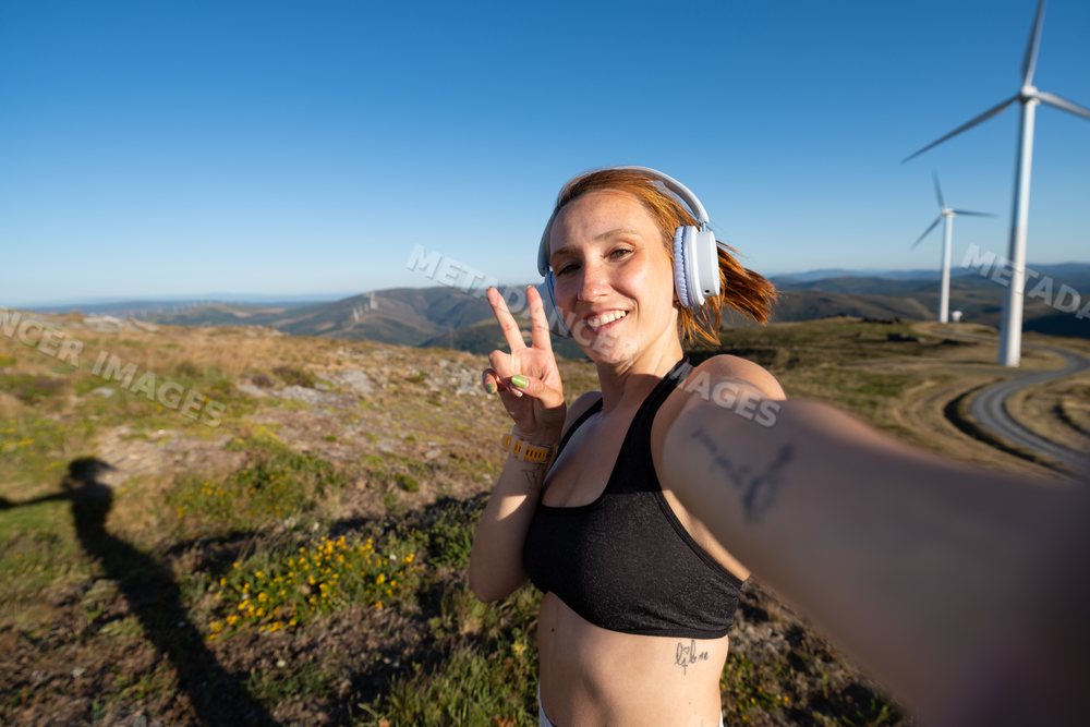 Young white woman takes a selfie at a wind farm in Galicia, Spain
