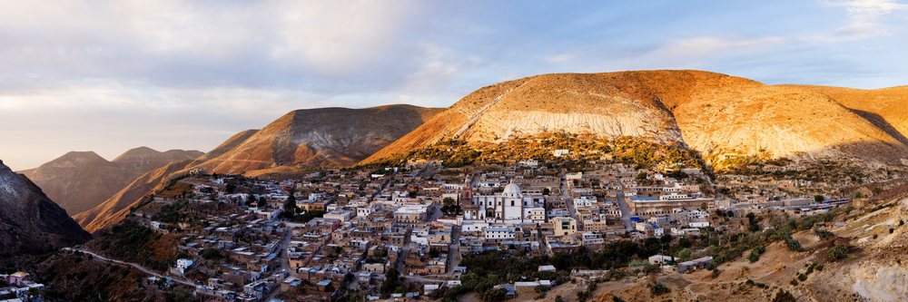Panoramic view of Real de Catorce village in arid mountains of San Luis Potosi at sunset showing a church and settlement, Mexico.