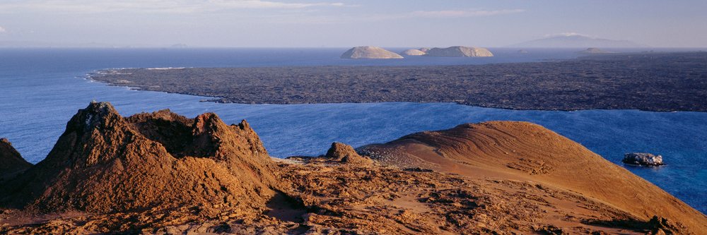 Volcanic craters and lava fields on Isla Bartolome overlook the ocean with distant islands visible in the Galapagos Islands, Ecuador, Volcano Craters Isla Bartolome, Galapagos Islands Ecuador.