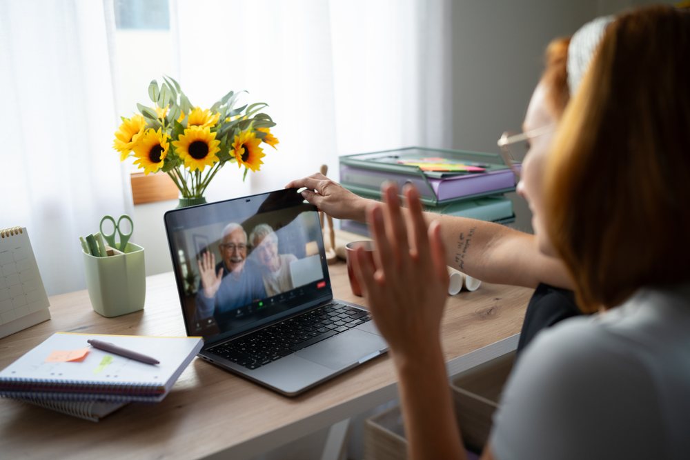 A white woman video calls an elderly couple from her home office