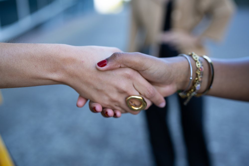 Two people shaking hands outdoors symbolizing connection and partnership, Spain.