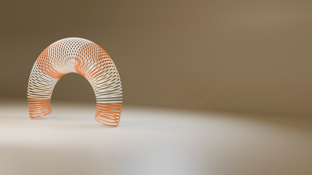 Curved orange and white plastic spring toy isolated against a neutral background in a studio setting.