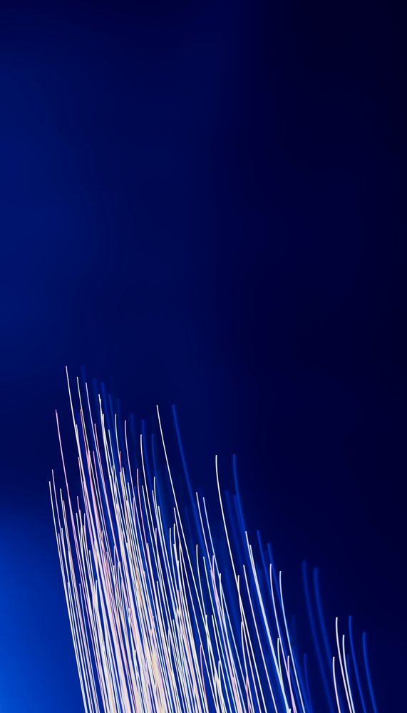 Light trails from colorful sources creating abstract streaks of light on a dark blue background.