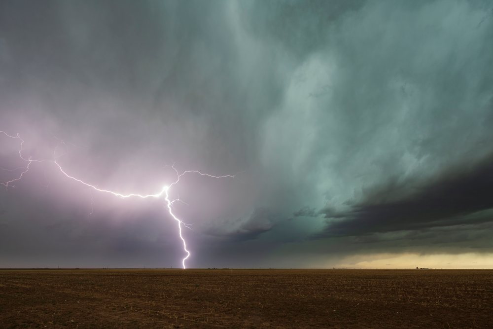 Lightning bolt strikes over a flat plain under dark storm clouds, USA within Tornado Alley, Storm Chasing, Weather, Environment, Floydada, Texas.