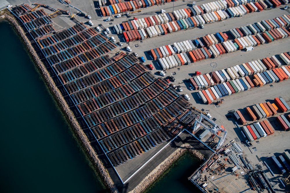 Container yard with stacked shipping containers, trucks, and cranes at a major port in Long Beach, a major port in Long Beach, CA, USA.
