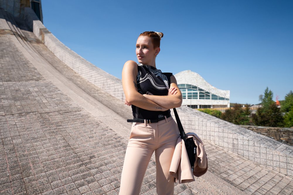 Adult woman stands outdoors with crossed arms against modern architecture and clear blue sky, businesswomen, Spain.