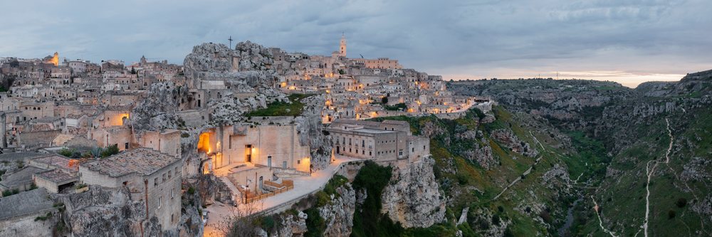Historic rock-cut buildings of Matera's Sasso Caveoso overlook the Gravina River gorge at Dawn, Basilicata, Italy.