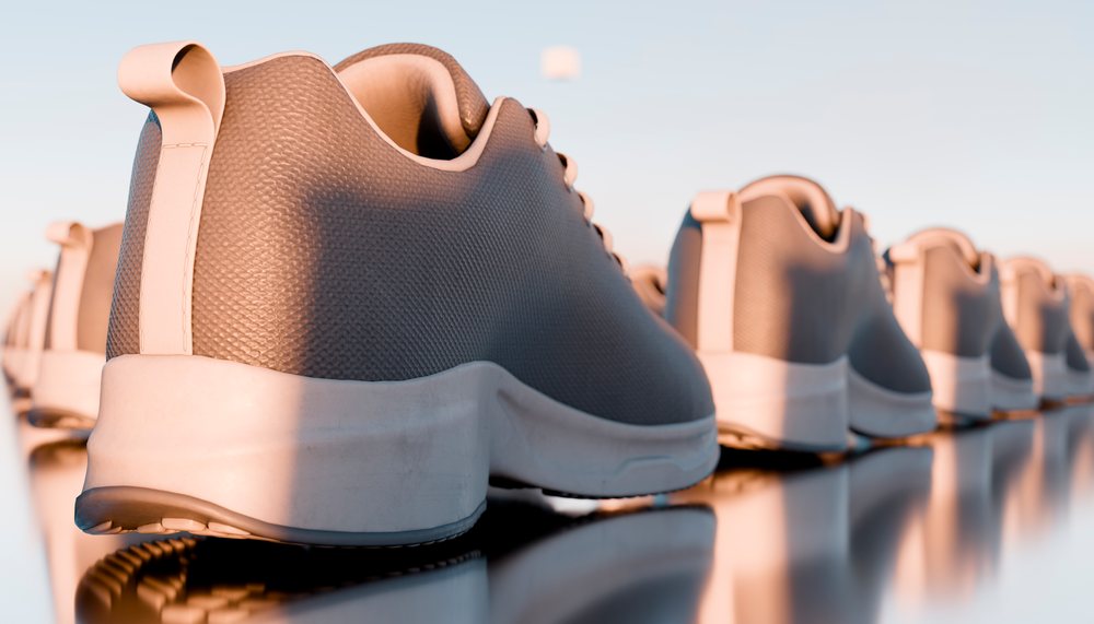 Row of athletic shoes with reflections on a glossy surface in a studio setting.