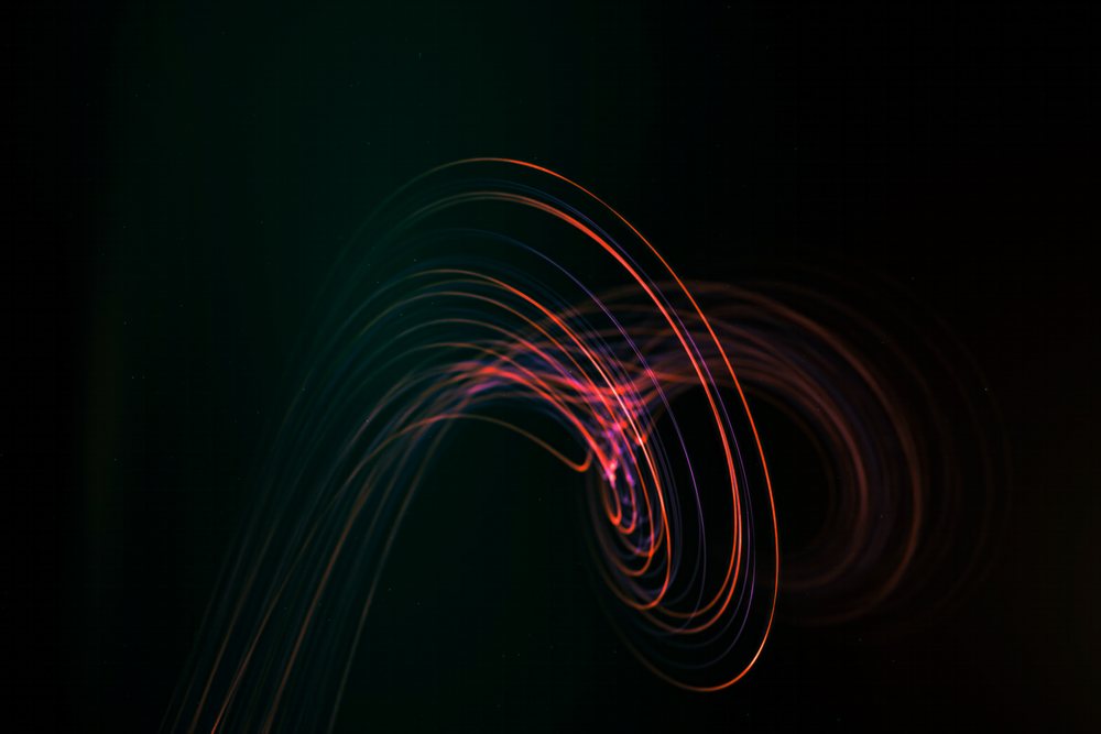 Colorful abstract light trails form curved patterns on a dark background.
