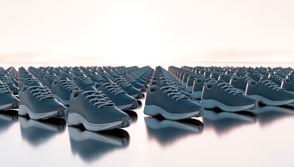 Rows of blue sneakers with white soles arranged in an orderly pattern on a reflective surface.
