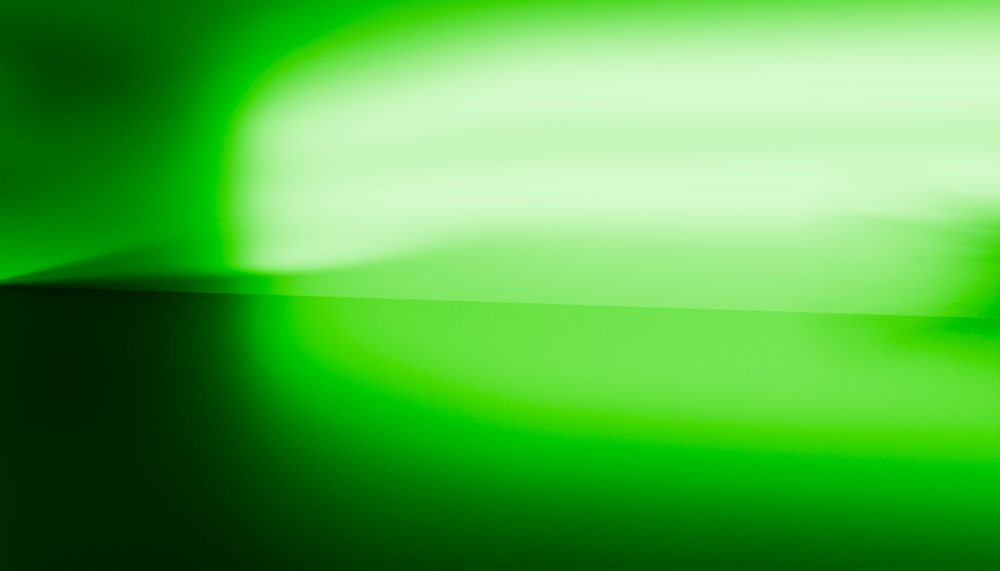 Green light and shadow create a smooth abstract gradient on an interior wall corner with modern minimalist style.