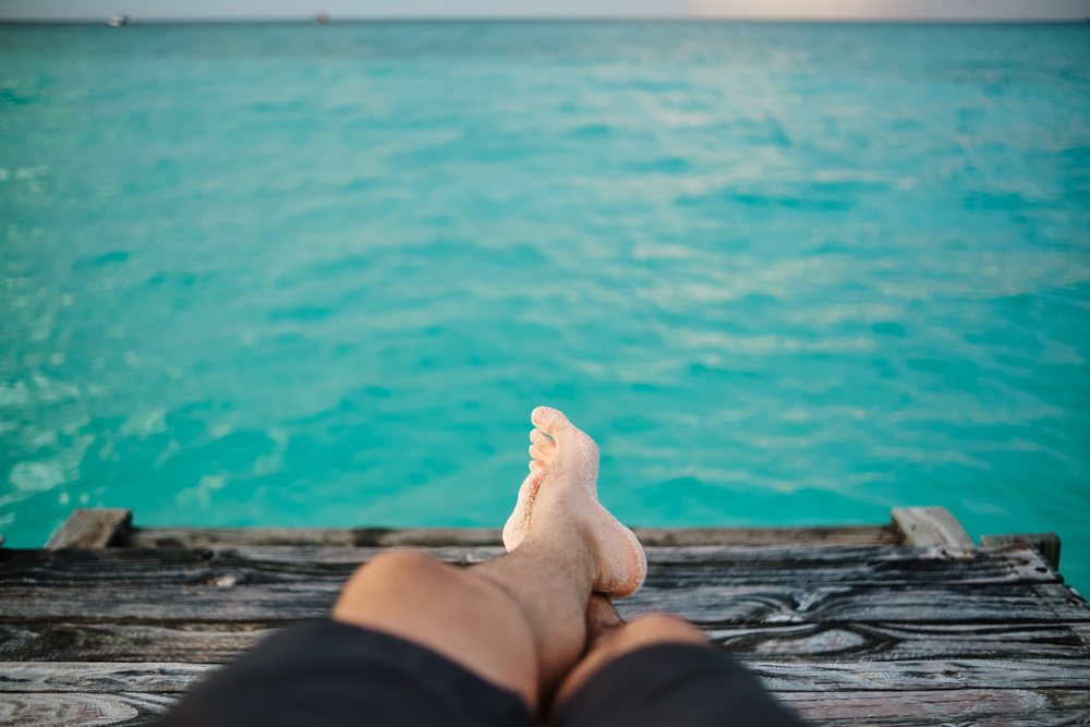 A person relaxing on a wooden pier overlooking turquoise water