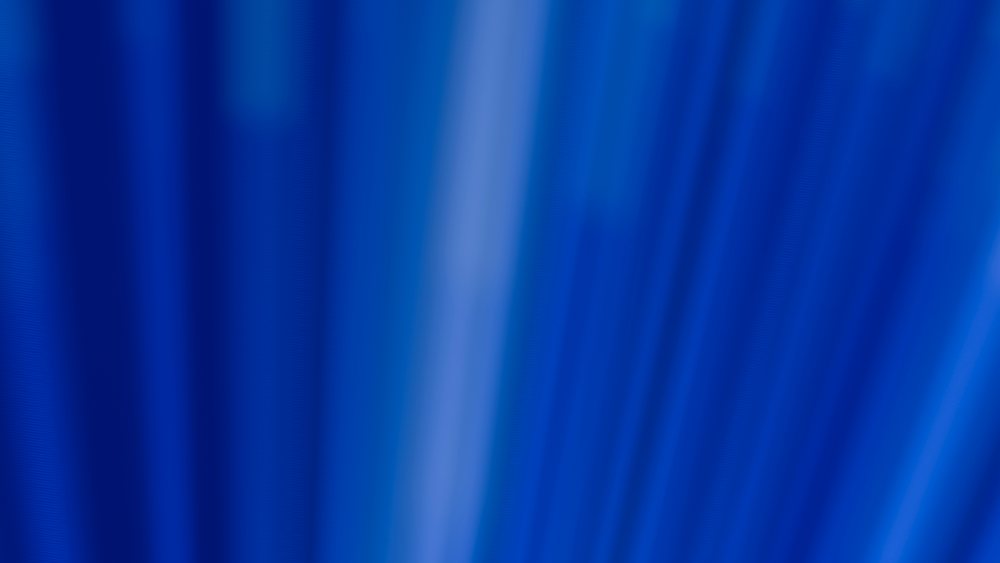 Blue fabric with soft flowing folds forms a smooth textured abstract background.