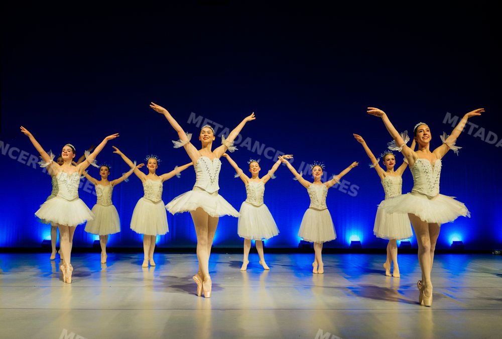 Female ballet dancers perform a graceful group dance on stage