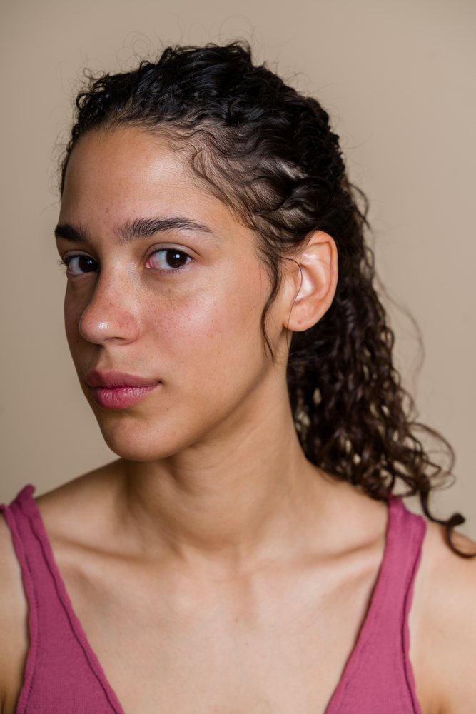 Young woman with curly hair and natural skin poses in a studio portrait by Pixelcreative studio, beauty shoot, Spain.