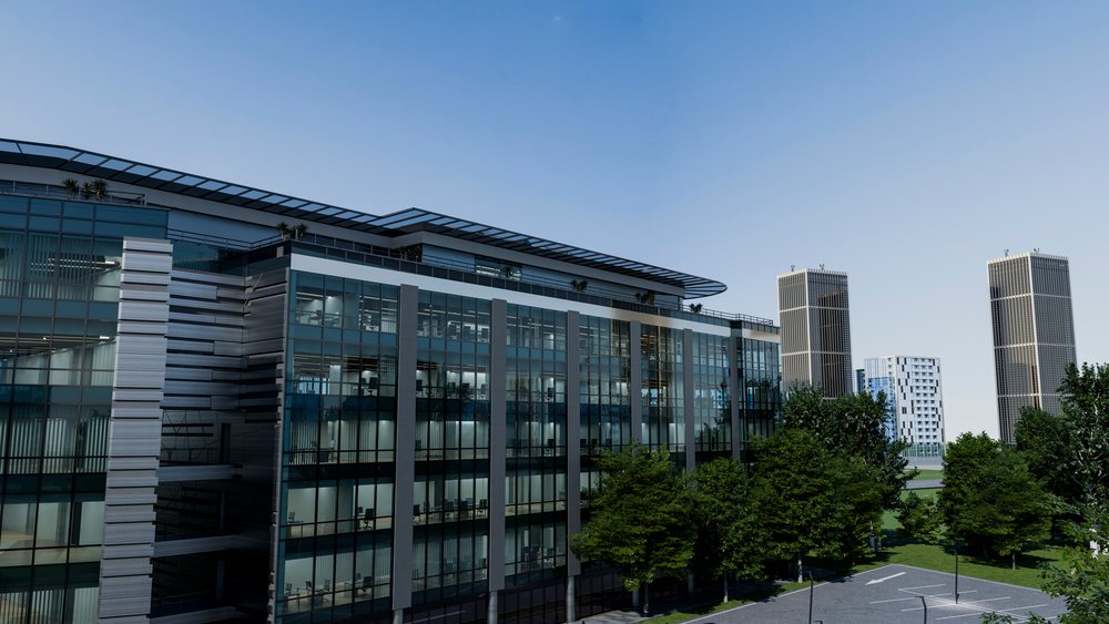 Modern office building with glass facade beside trees and parking lot under a clear blue sky with skyscrapers in background.