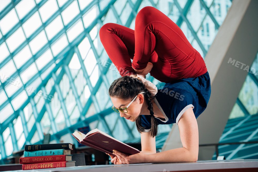 Young woman reading a book while doing a yoga pose