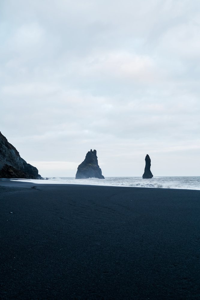 Black sand beach with ocean rock formations