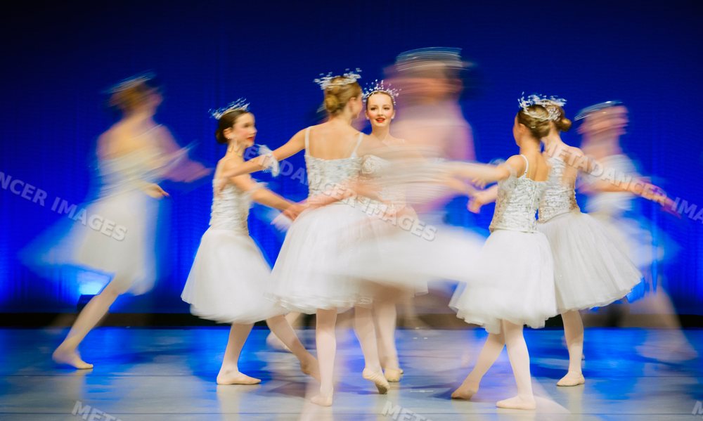 Young ballet dancers performing together on stage in white tutus