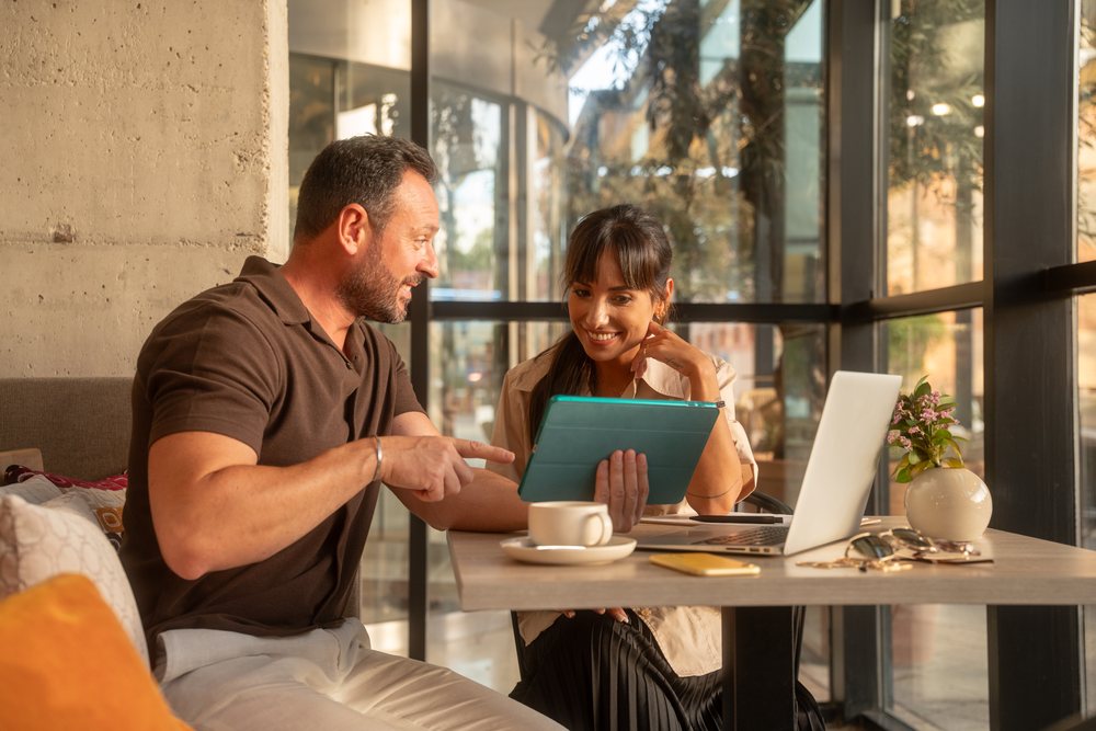 Two coworkers collaborate using a tablet in a modern office workspace, business, coworker, Seville, Andalucia.