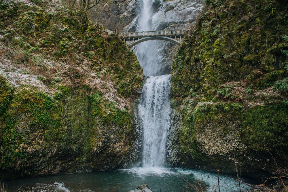Multnomah Falls cascading in two tiers below an arched pedestrian bridge above a pool, Bridal Veil, Oregon.
