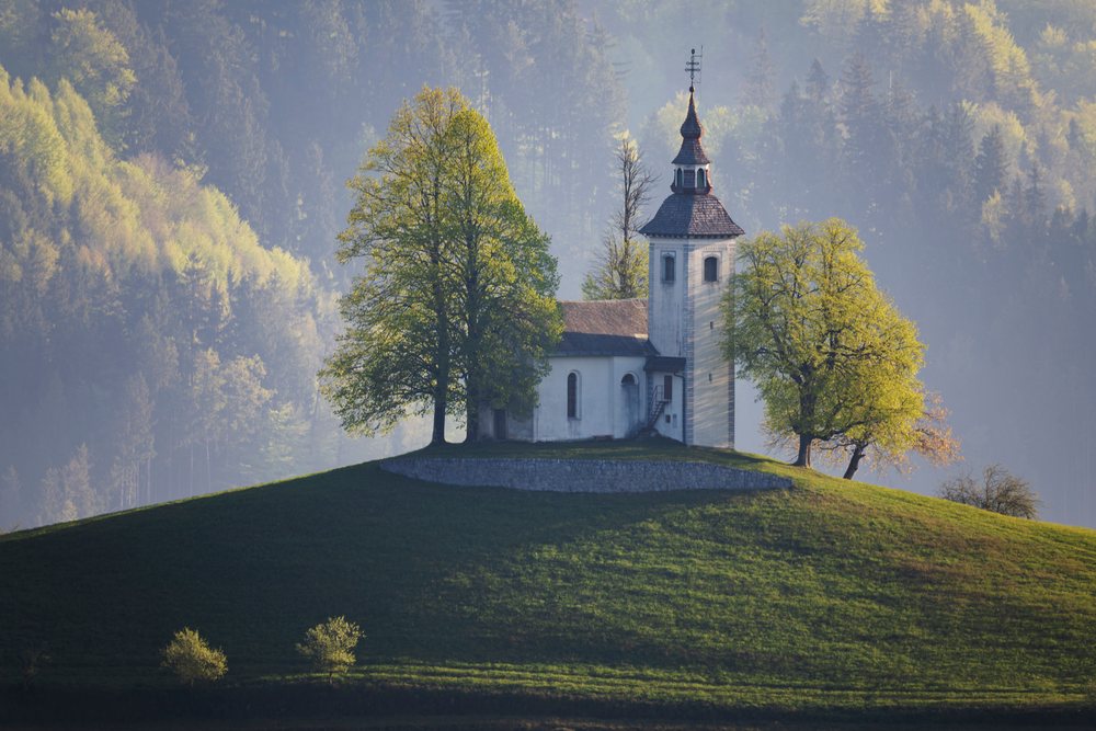 St Thomas's Church stands on a grassy hill, landscape, cityscape, Škofja Loka, Slovenia.