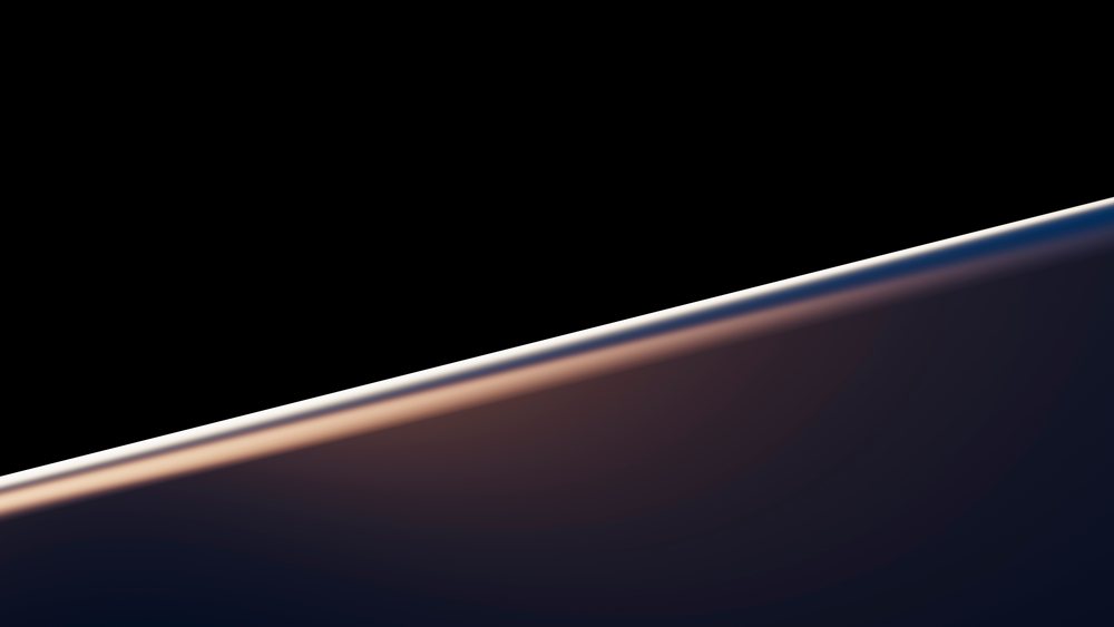 Curved glass edge with reflected light against a black background in a studio setting.