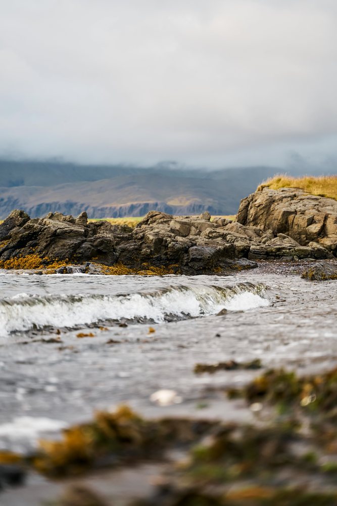 A small wave breaks on the rocky shoreline of Iceland's coast