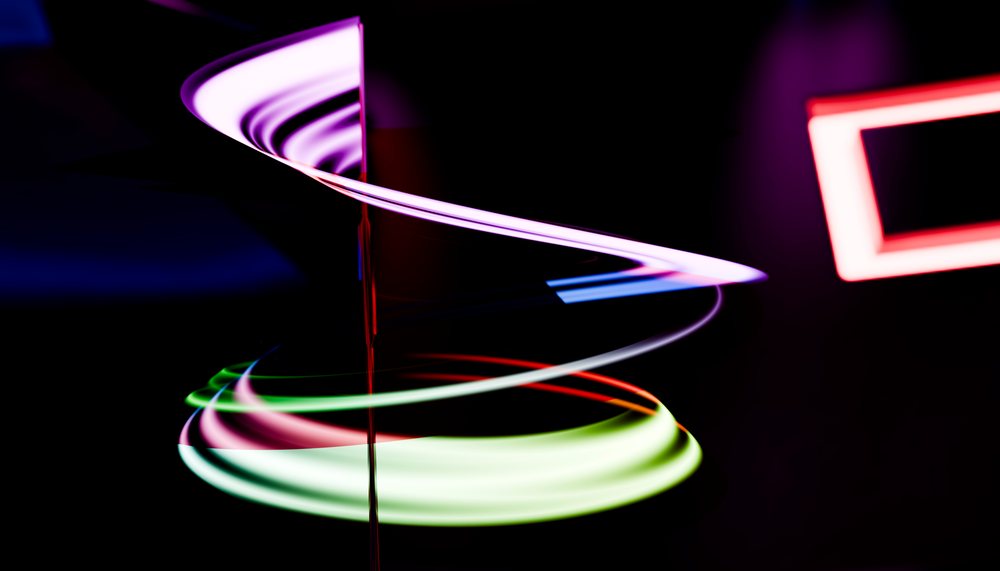 Light trails forming a colorful spiral shape against a dark background in an abstract artistic setting.