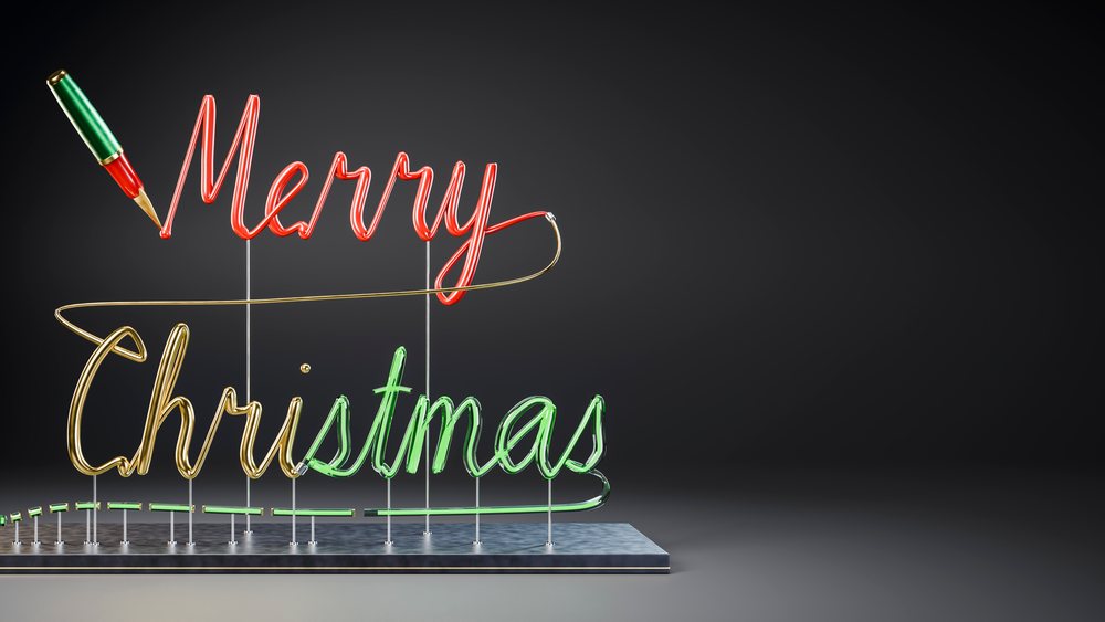 Merry Christmas neon light sign with red, green, and gold colors on a dark background mounted on a metal base with supports.