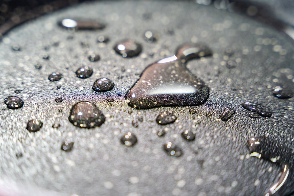 Macro photograph of water droplets resting on a shiny textured metal surface with visible reflections, texture, abstract texture, background, wallpaper, Spain.