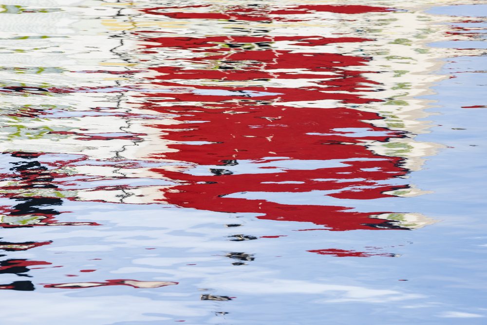 Rippling water surface, reflects colorful red and white buildings vividly, Landscape, Henningsvaer, Lofoten, Norway.