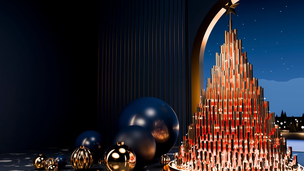Metallic Christmas tree with red lights and star decoration indoors next to gold and blue ornamental spheres at night.
