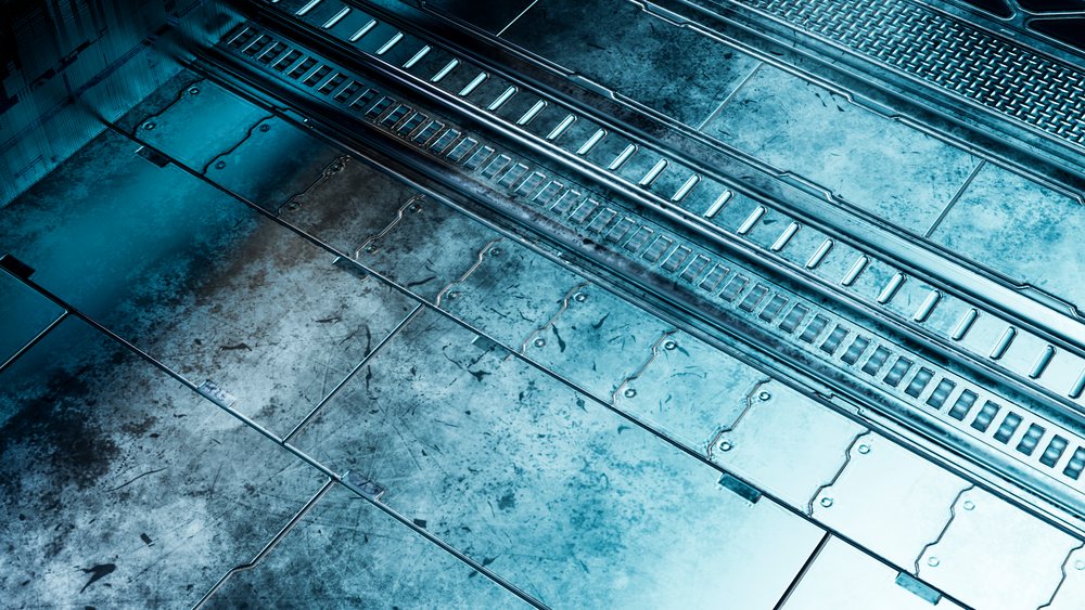 Metal industrial floor with scratched, worn panels and grated sections in a factory or workshop interior.