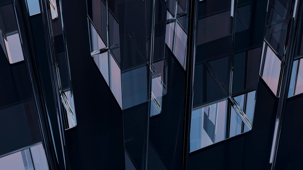 Reflections on glass windows highlight architectural details of a modern building exterior.