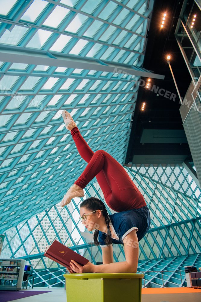 A woman balances in an acrobatic pose while reading inside the Seattle