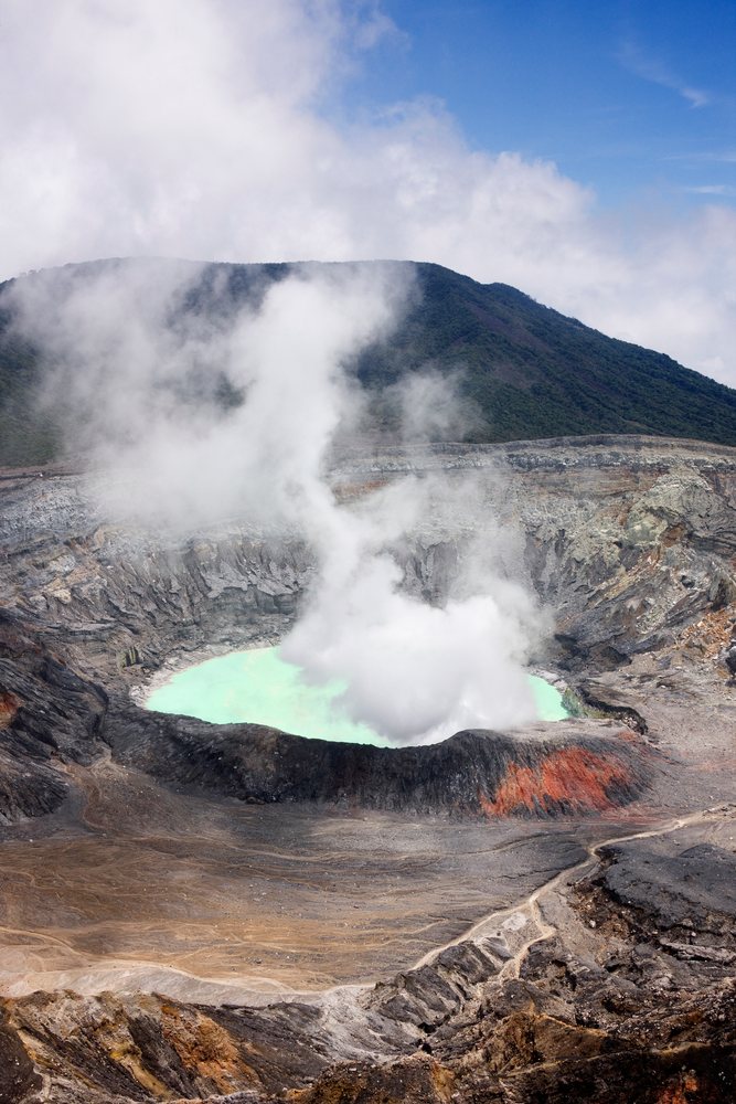 Poas Volcano crater emits steam from its acidic crater lake amid rocky terrain, Costa Rica, Central America.
