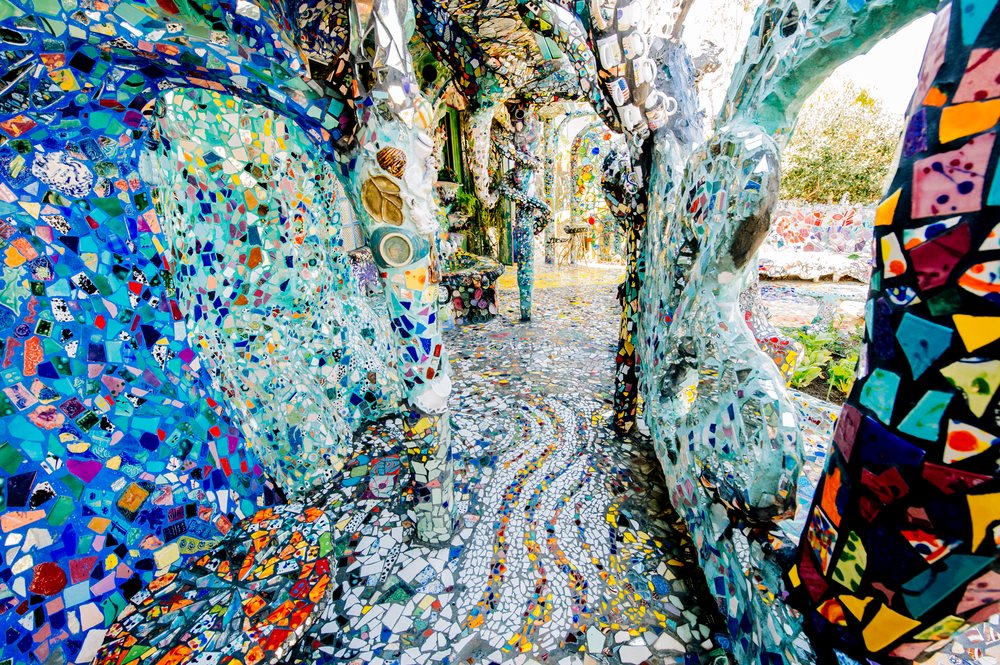 Colorful mosaic tiles form an artistic outdoor walkway and decorative benches with sculptural mosaic elements under natural sunlight in California, USA.