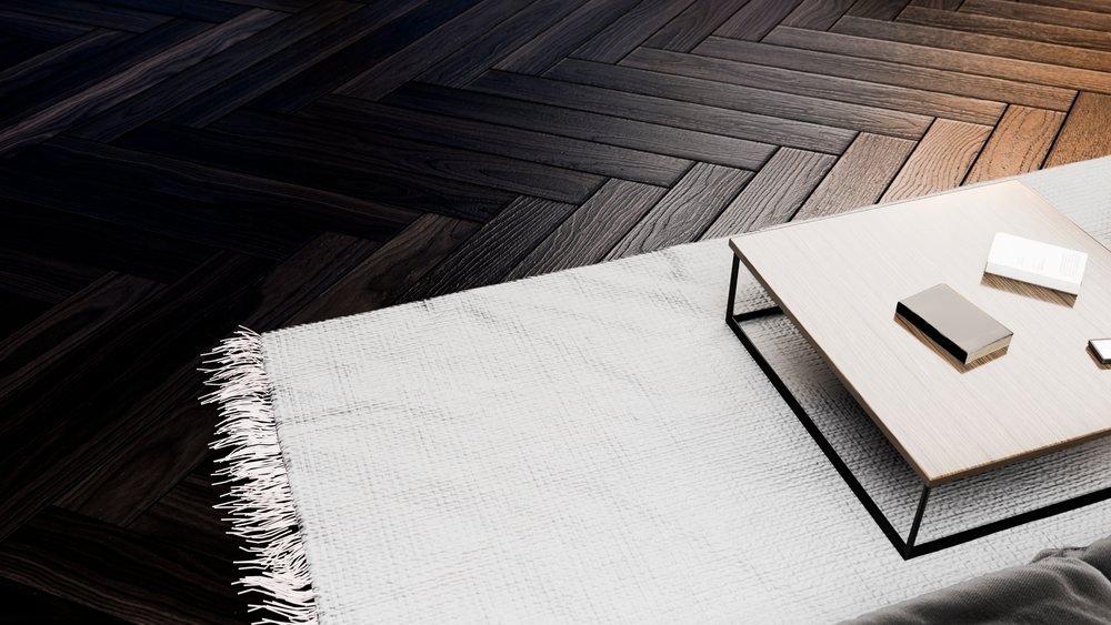 Rectangular coffee table with books on a white fringed rug over dark wood floor in a modern interior.