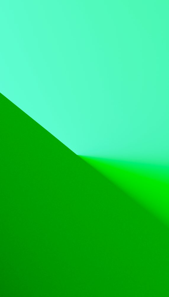 Close-up of the corner where green and blue textured papers meet with shadowed fold creating geometric shapes.