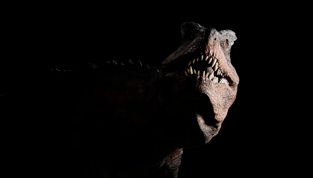 A close-up image of a T-Rex dinosaur with jaws open