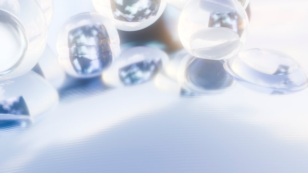 Transparent water droplets rest on a smooth reflective surface under soft natural light.