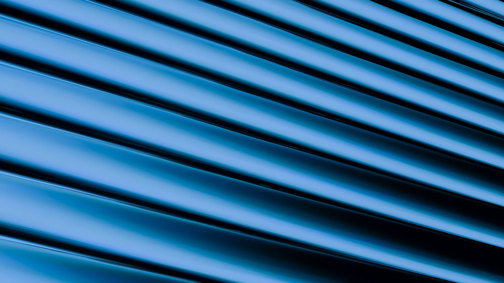 Abstract blue rendering featuring diagonal shiny metallic lines with a smooth surface texture.