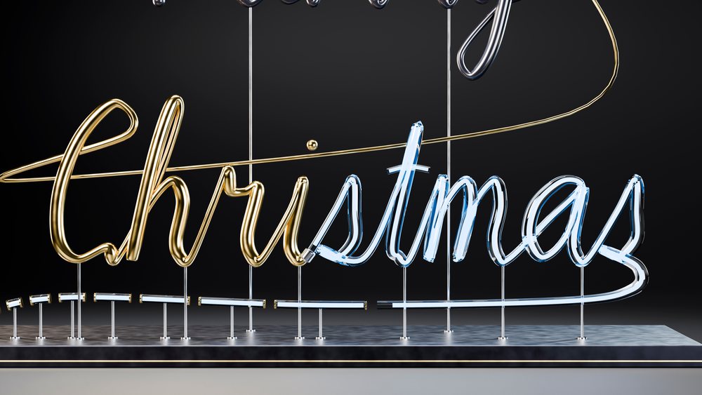 Glowing gold and blue Christmas neon sign mounted on metal stands against a black background.