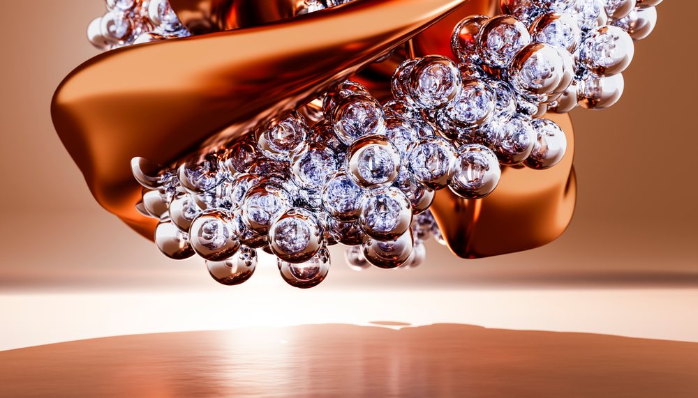 Transparent glass spheres clustered together with a reflective metallic abstract form in a studio setting with an orange background.