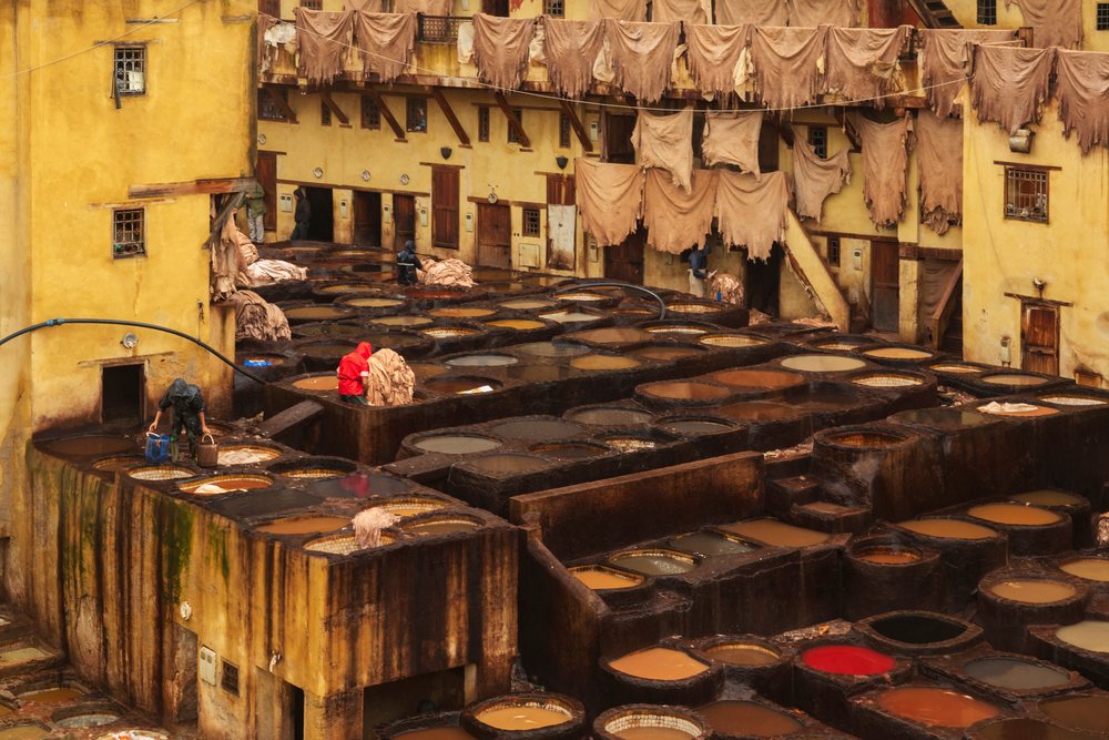 Workers in rain gear process leather hides in water-filled tanning pits at the Chouara Tannery, during pouring rain, Landscape, Lifestyle, Fes, Fes-Mekners Administrative Regio, Morocco.