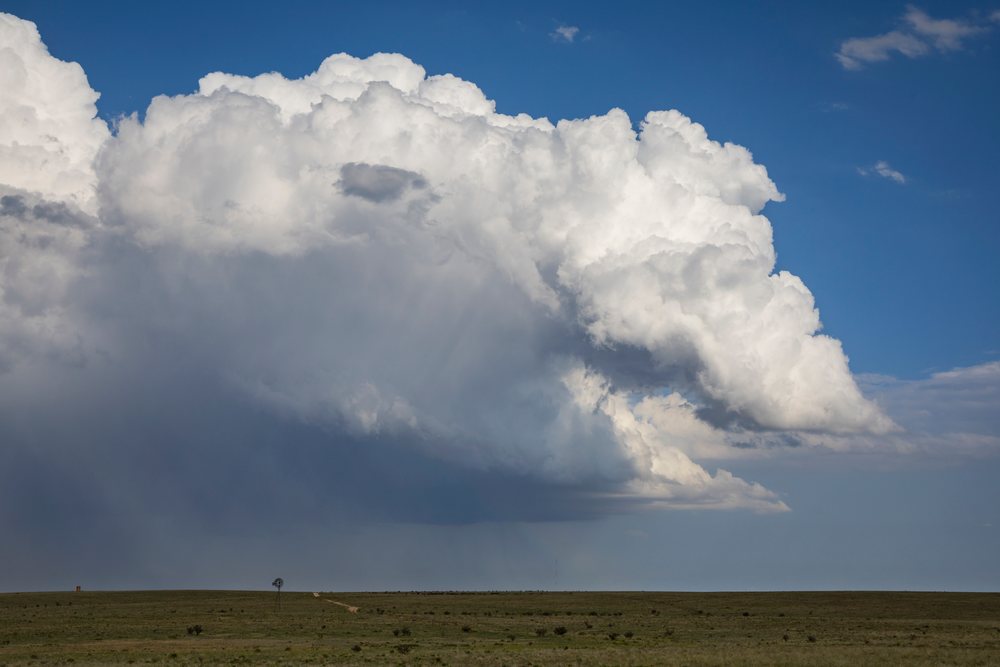 Cumulus storm clouds form over open grassland plains near a windmill, Vaughn, New Mexico, USA.