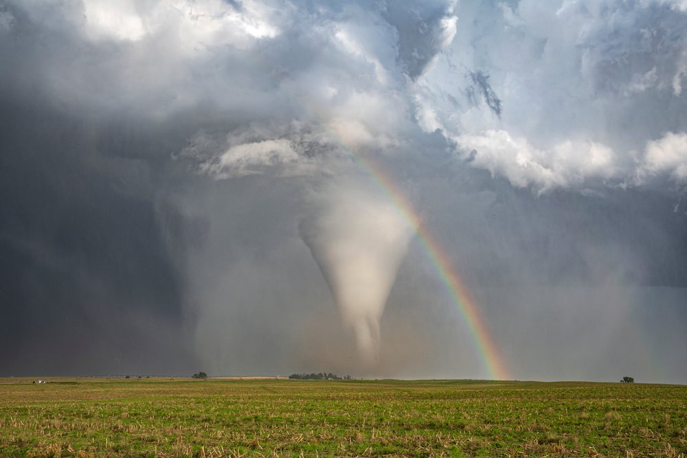 Tornado with an accompanying Rainbow forms over a grassy field during storm chasing, Dickens, Nebraska, USA.